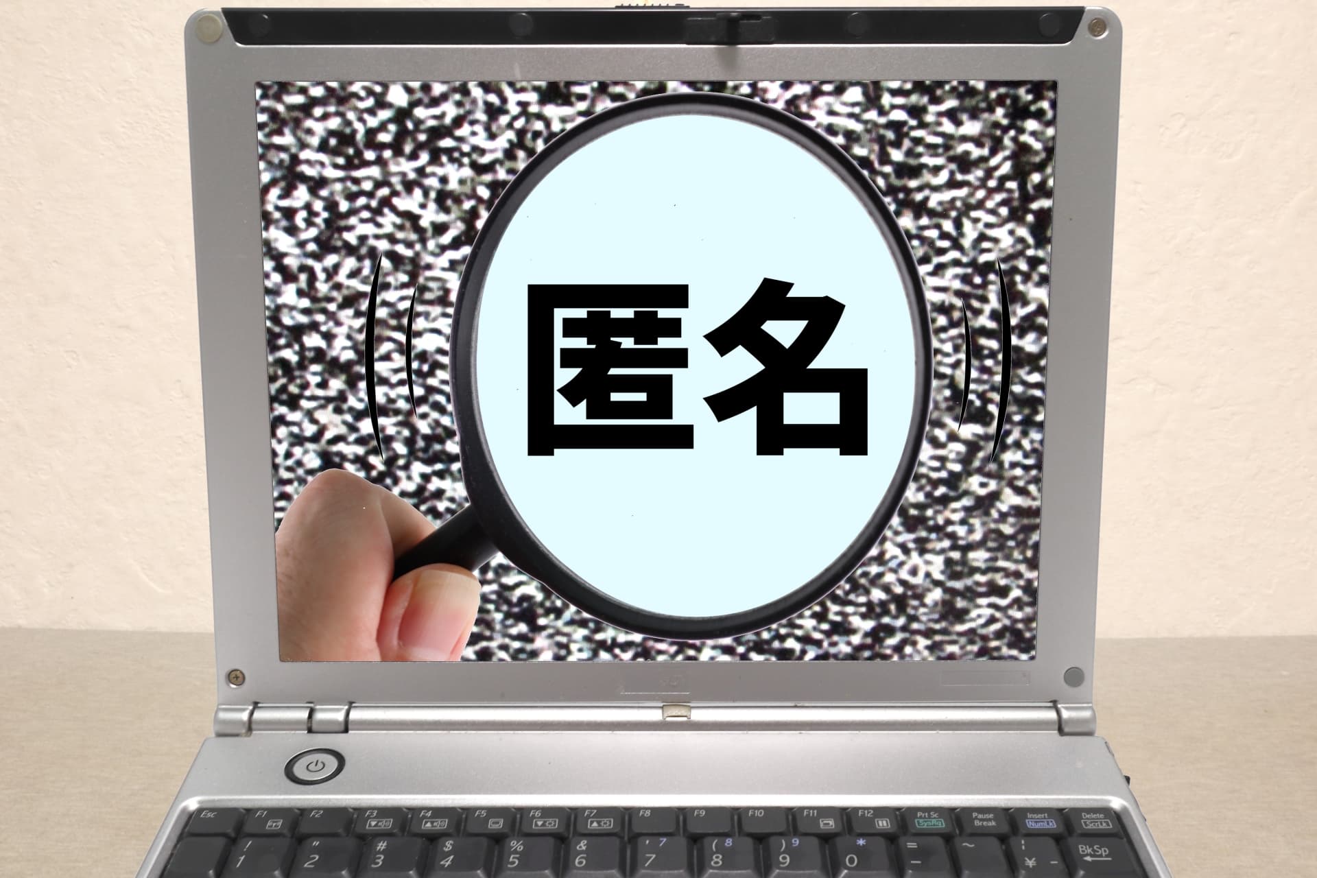 パソコンの前に匿名と書いた虫眼鏡の画像