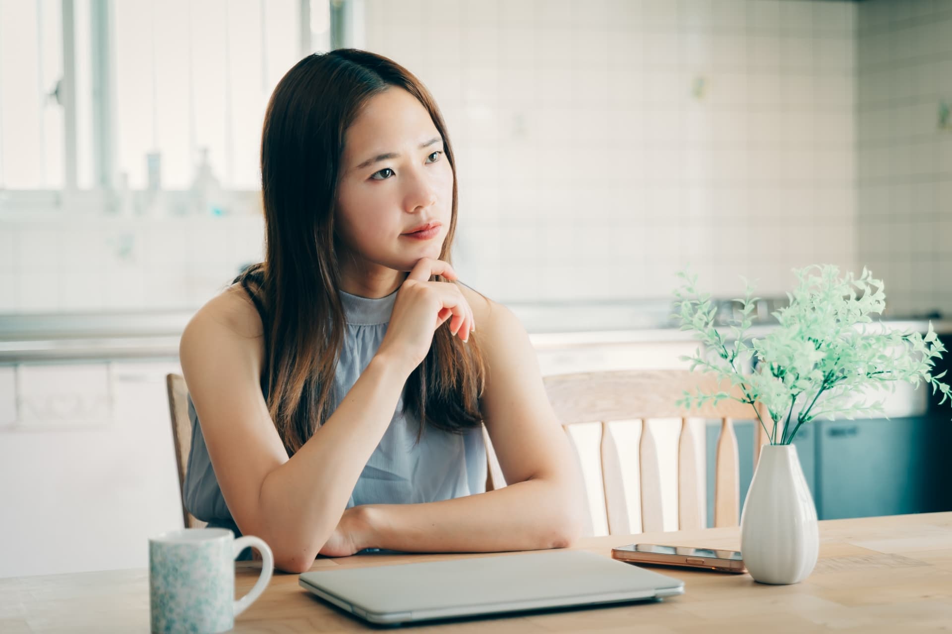 自宅でパソコンの前で悩む女性
